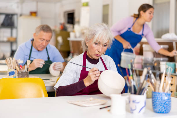 Seniors in classroom with instructor painting ceramics